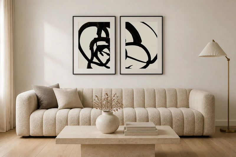 Pair of black and white abstract Atienne prints framed in matte black, hung above an oatmeal boucle sofa in a sophisticated McGee-style living room