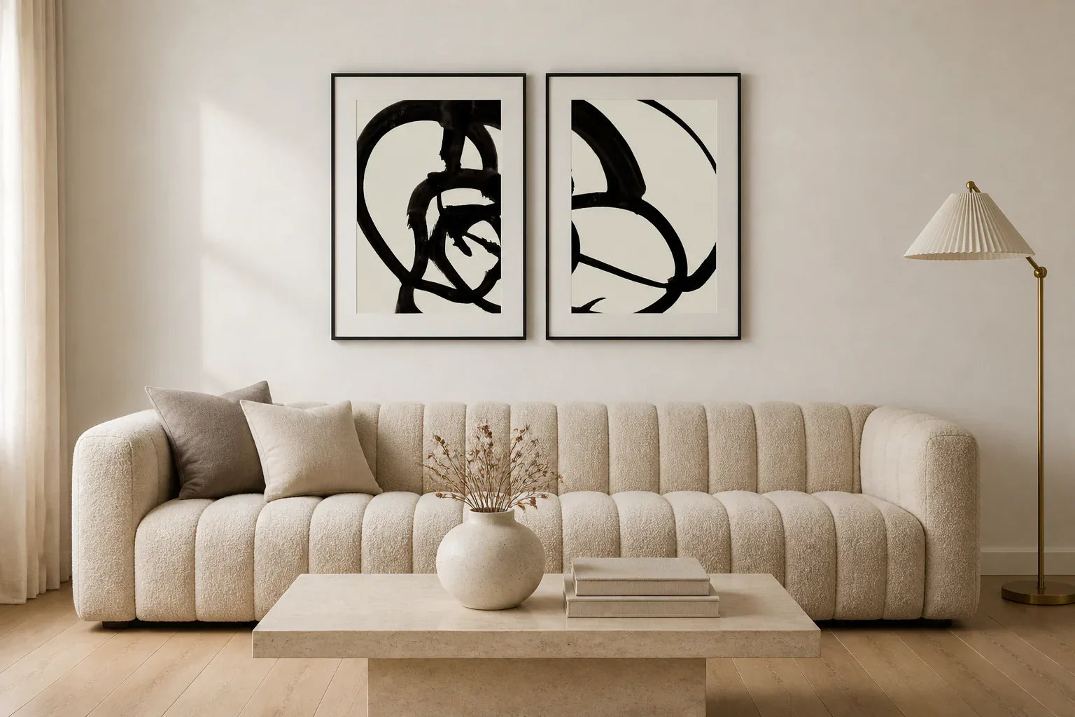 Pair of black and white abstract Atienne prints framed in matte black, hung above an oatmeal boucle sofa in a sophisticated McGee-style living room