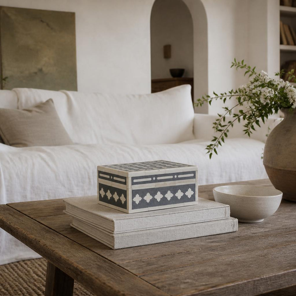 Bone inlay box on a weathered oak coffee table in a white linen living room