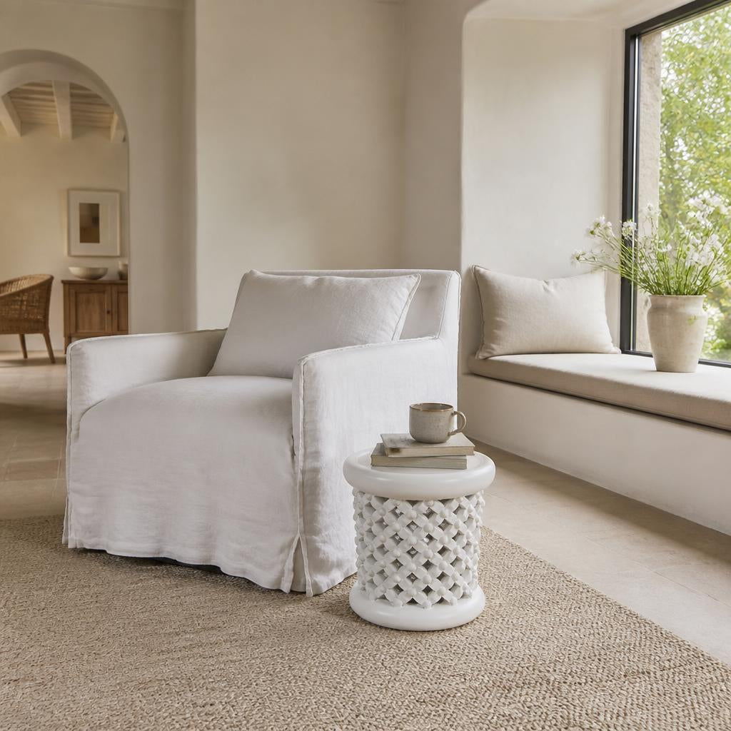 White Bamileke stool as a side table beside a linen armchair